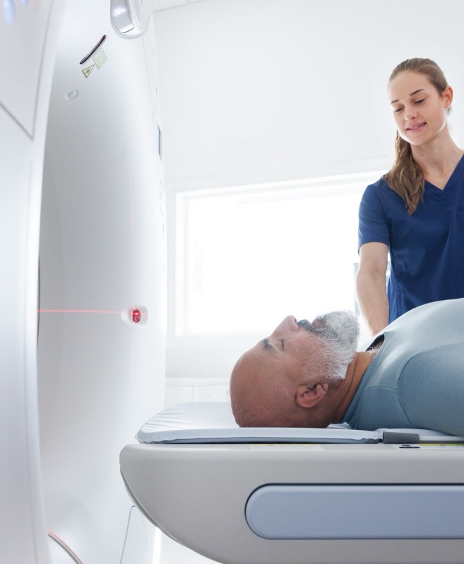 A medical assistant setting up a patient in an MRI scanner