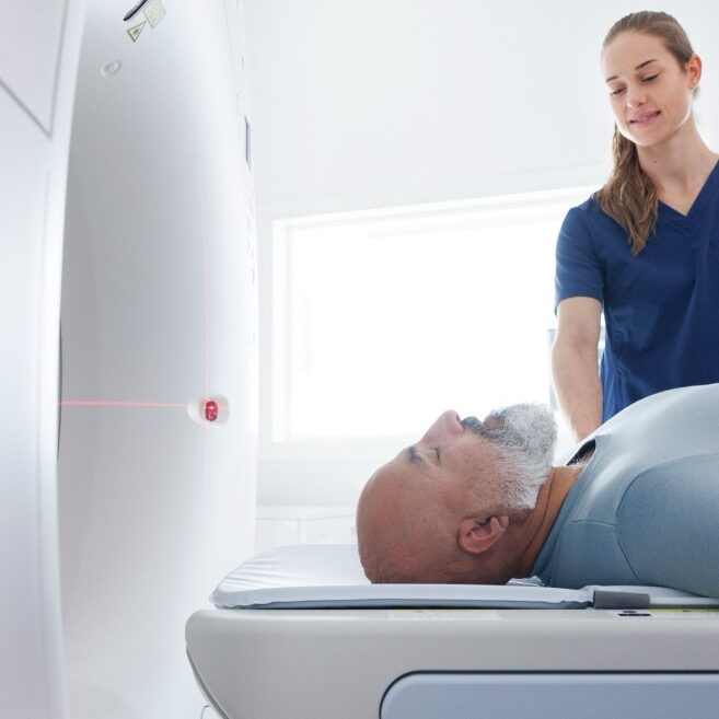A medical assistant setting up a patient in an MRI scanner.